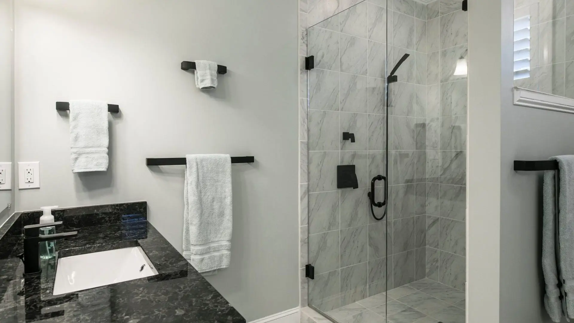 black and white vanity; glass shower; towel bars