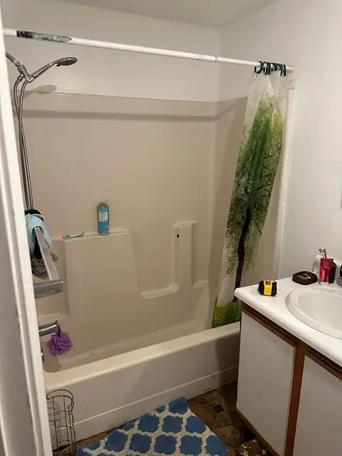 Before image of a bathroom showing old tiles and outdated amenities.