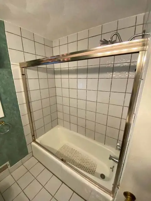 Before image of a bathroom with worn-out fixtures and outdated design elements.