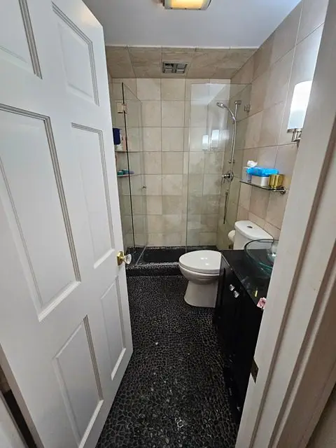 Before image of a dated bathroom with worn-out features and poor lighting.